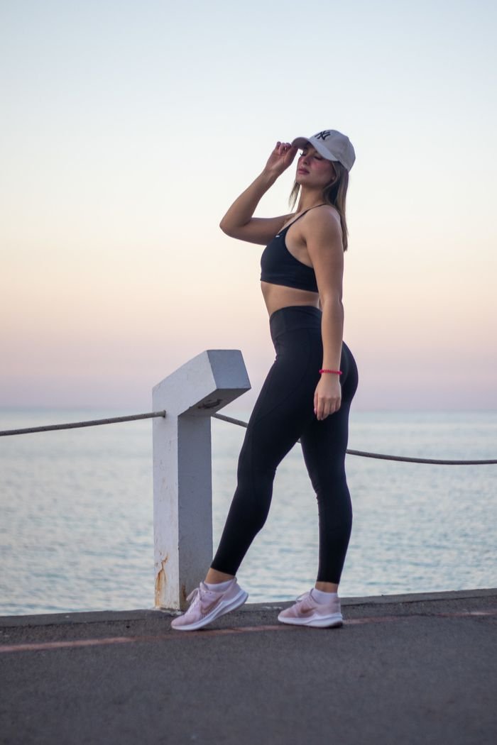 Young woman in sporty attire posing by the sea at sunset in Mahdia, Tunisia.